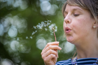 Woman blowing on a dandelion clock
